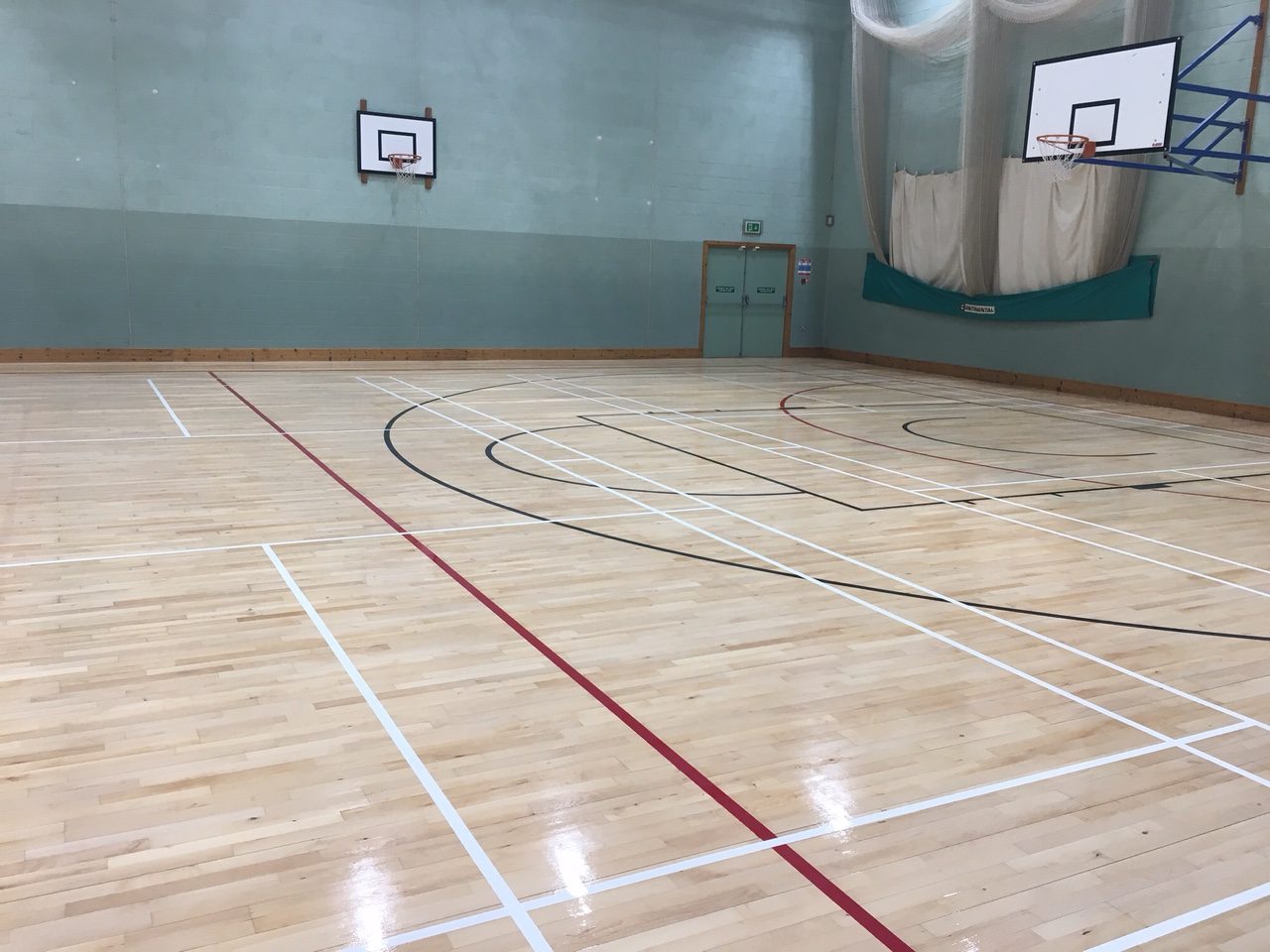 Indoor timber sports hall floor with court markings for leisure centre