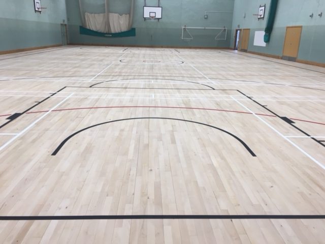 Indoor timber sports hall floor with court markings for leisure centre