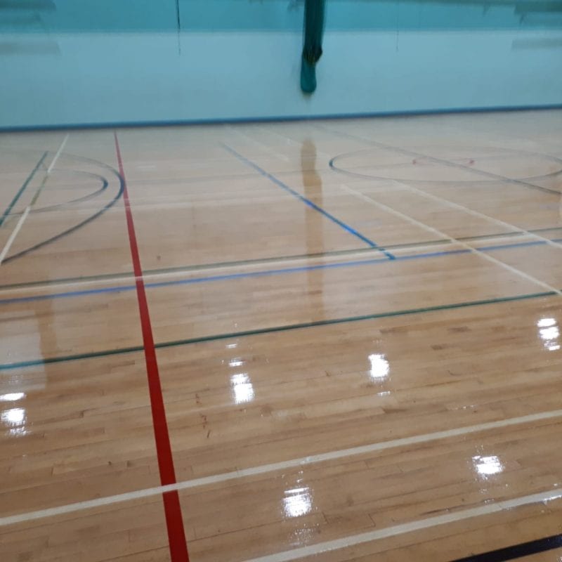 Castell Alun High School in Wrexham. The team replaced defective sections of the timber floor, scrubbed and applied a clear polyurethane seal and finally re-marked the netball courts.
