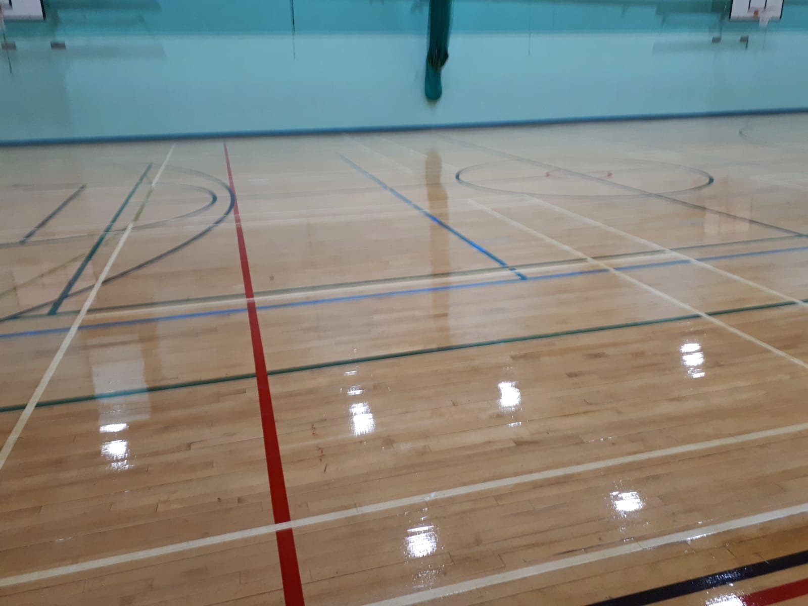 Castell Alun High School in Wrexham. The team replaced defective sections of the timber floor, scrubbed and applied a clear polyurethane seal and finally re-marked the netball courts.