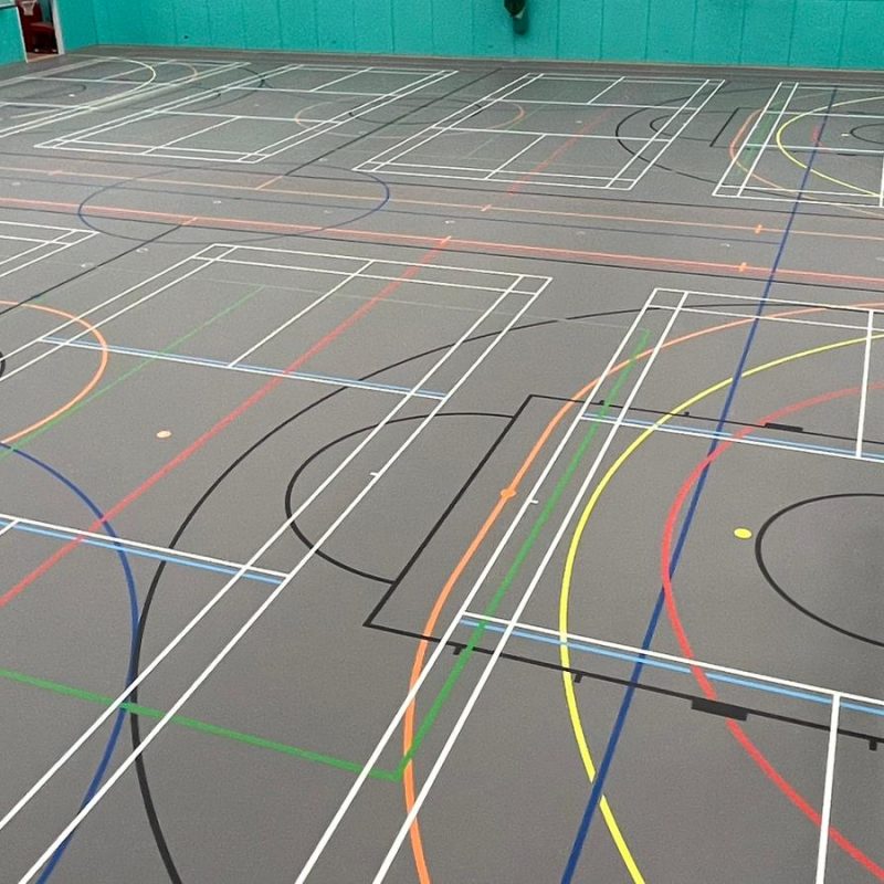 Close-up of pale blue pickleball court lines overlaid on indoor Pulastic sports flooring